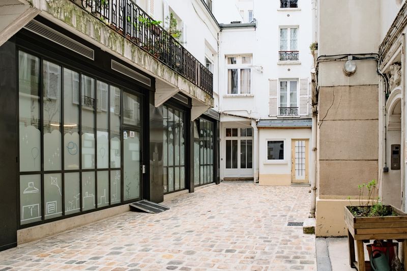 Cour intérieure pavée menant à l'entrée vitrée du Show'dron
